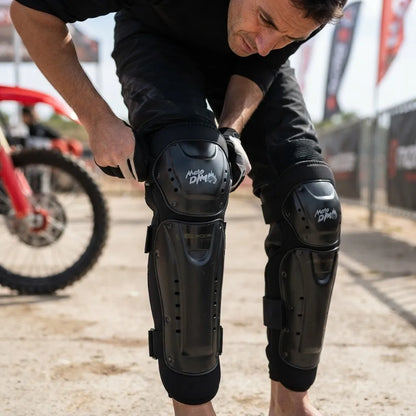 Hombre ajustándose las rodilleras de protección junto a una moto